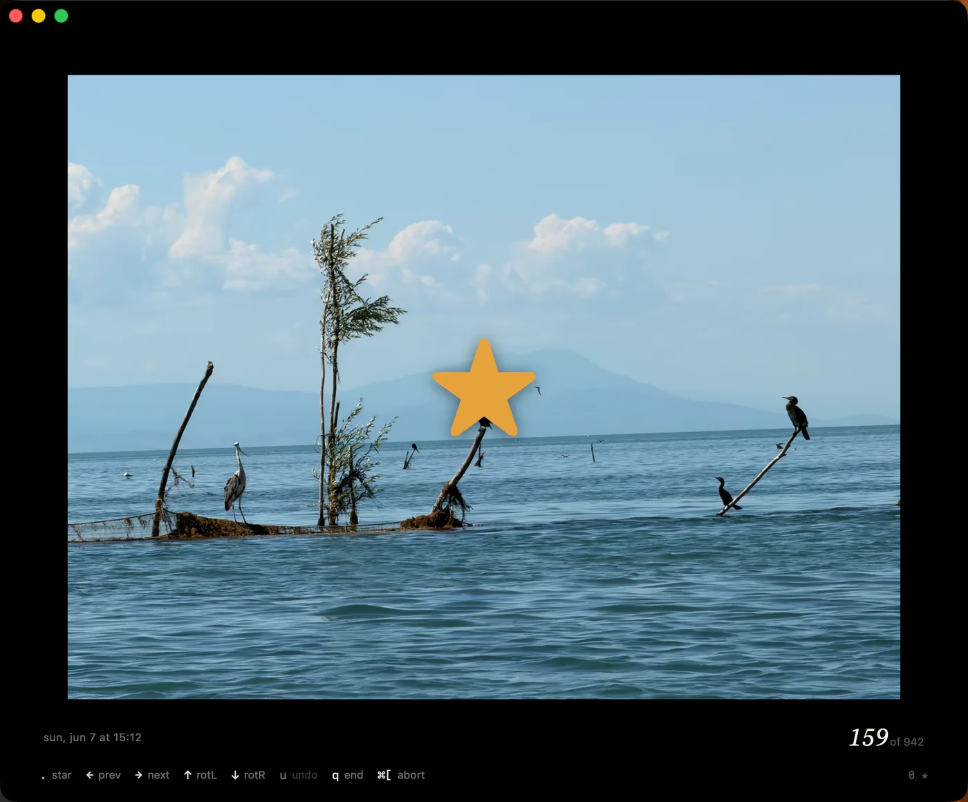 PhotoTriage favorites sweep on macOS: a lakeside photo full-screen with a big amber star marking it as favorited, above the sweep's short legend — dot star, arrows prev and next, rotate, u undo, q end — with the capture date and the position, 159 of 942